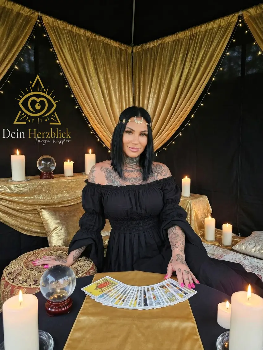 Tanja Kasper mit aufgefächerten Karten vor goldenen Vorhängen und Kerzen